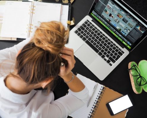 Woman stressed out on laptop with notebook