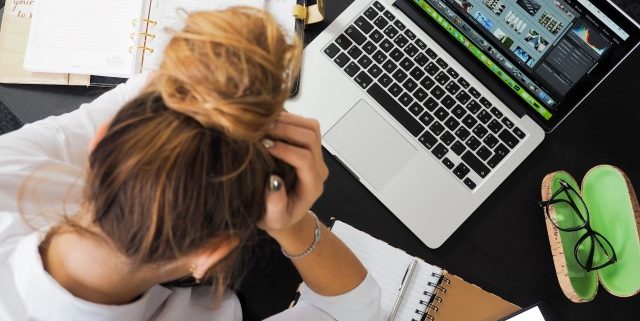 Woman stressed out on laptop with notebook